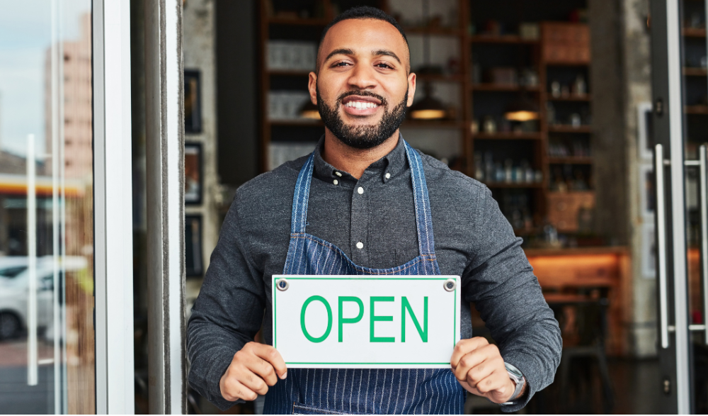 A small-business owner standing in front of a newly opened storefront funded by an economic development loan